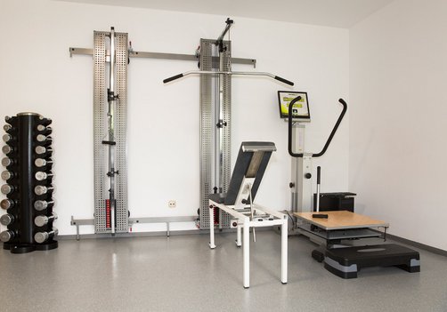 Moderne Fitness- und Krankengymnastikgeräte in der Physiotherapie Hildebrand in Moosach München, inklusive Hanteln, Zugapparaten und Trainingsplattform. Moderne Ausstattung für Krankengymnastik bei Physiotherapie Hildebrand