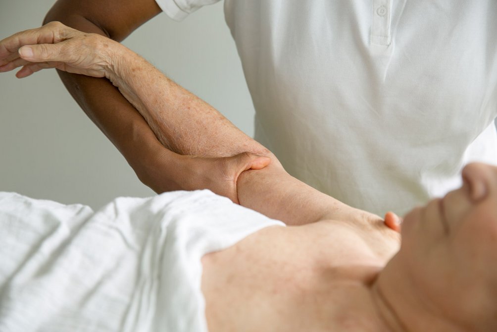 In der Praxis Hildebrand steht der Patient im Mittelpunkt. Nahaufnahme einer manuellen Nacken- und Schulterbehandlung von hinten.